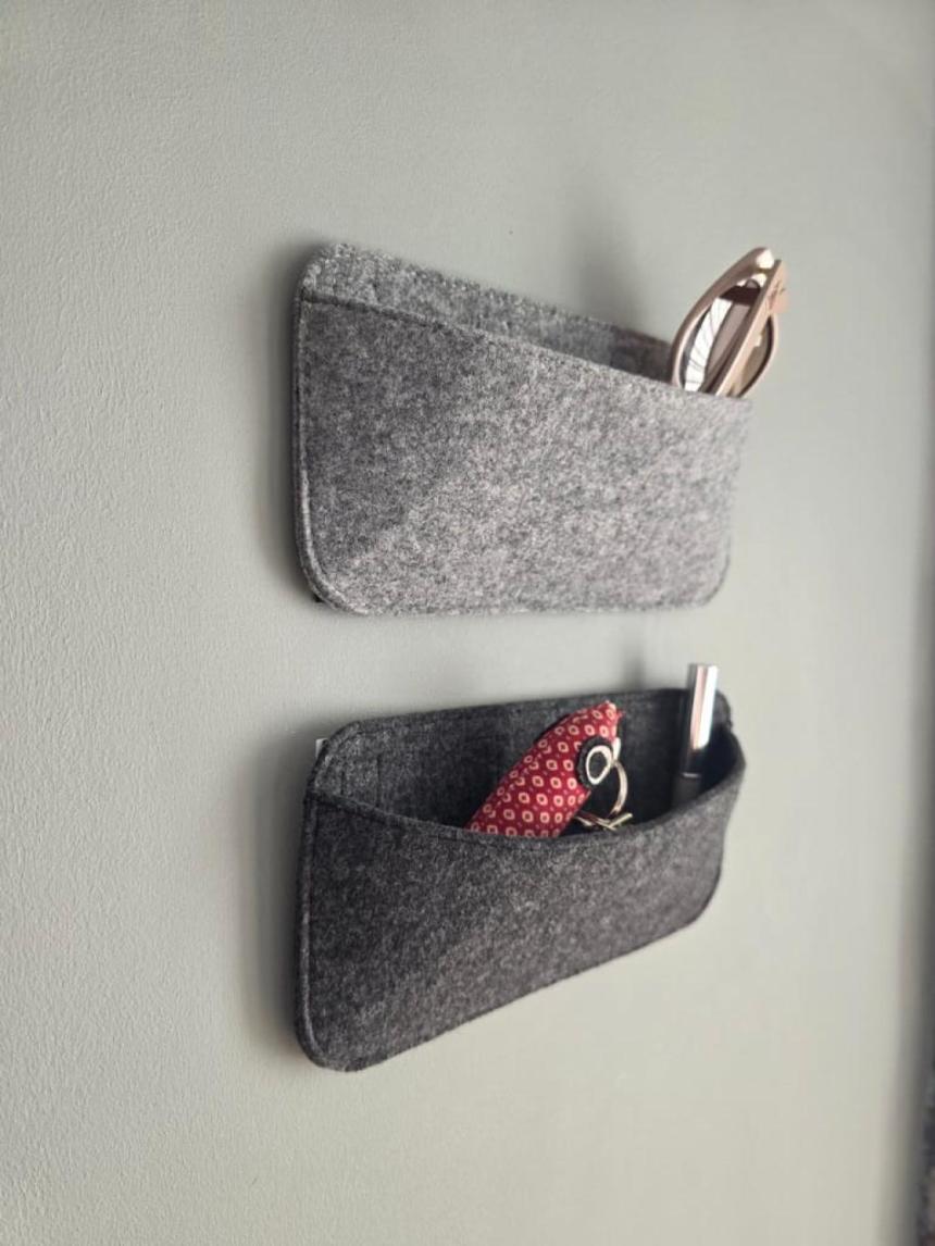Camper Organizer aus Filz an der Seitenwand im Wohnwagen, mit Brille und Kabeln befüllt
