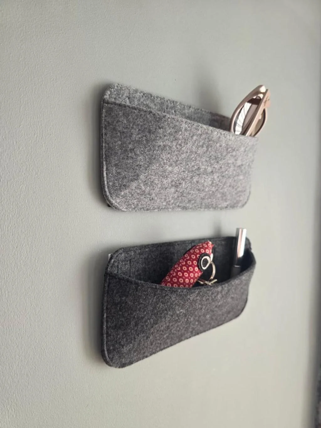 Camper Organizer aus Filz an der Seitenwand im Wohnwagen, mit Brille und Kabeln befüllt
