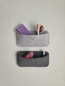 Camper Organizer aus Filz an der Seitenwand im Wohnwagen, mit Brille und Kabeln befüllt