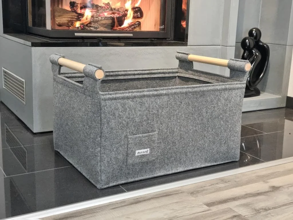 Ein Filzkorb mit Holzgriffen vor einem Kaminoffen